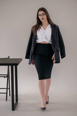 Kendine güvenen genç iş kadını modern ofis kıyafetleriyle kameraya doğru yürüyor, profesyonel tarzda..
