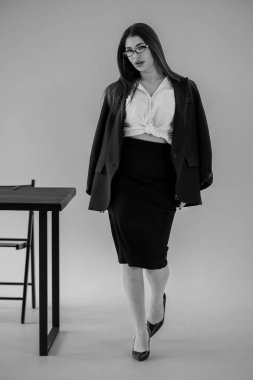 Siyah takım elbiseli profesyonel bir genç kadın stüdyoda, portre için poz veriyor, kendinden emin bir ifade..