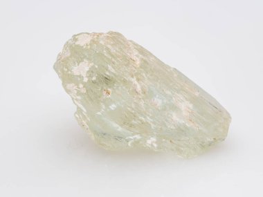 Çiğ, açık yeşil akuamarin kristali, çeşitli beril çeşitleri, temiz beyaz yüzey mineral numunesinde prizmatik şeklini ve soluk, sütlü rengini gösterir..