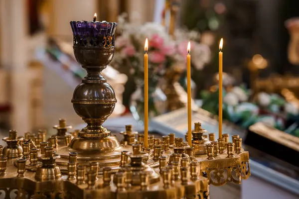 Bolca dekore edilmiş bir Ortodoks kilisesinin içinde mumlarla süslenmiş pirinç mum tezgahının huzurlu yakın görüntüsü,.
