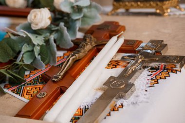Ortodoks düğün töreni ayrıntıları süslü haçların arasına yerleştirilmiş iki beyaz mum ve ahşap bir yüzeye işlenmiş geleneksel bir kumaş içeriyor..
