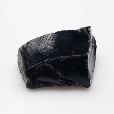 Cilalı, koyu siyah obsidyen bir kaya, hafif pürüzlü bir yüzeyi ve beyaz bir arka planda dinlenen yanardöner bir parıltı, camsı dokusunu sergiliyor..