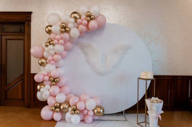 Balon Çelenk ve Melek Kanatlı Zarif Bebek Duş Arkaplanı: Çiçek Düzenleme ve Pastayla Yeni Doğan Bir Kız İçin Pembe ve Altın Temalı Kutlama.