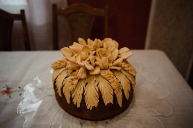 Karmaşık hamur çiçekleriyle süslenmiş geleneksel İtalyan panettone pastası sıcak aydınlatılmış bir yemek odası ortamında dantel kaplı bir masanın üzerinde duruyor..