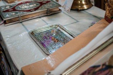 Ortodoks Düğün Töreni Detayları: Yüzüklü Gümüş Tepsi ve Beyaz Giysi Kitapları, Dini Ayarlar, Sembolik Nesnelere Odaklanma, Yumuşak Işıklandırma, Geleneksel Ayin.