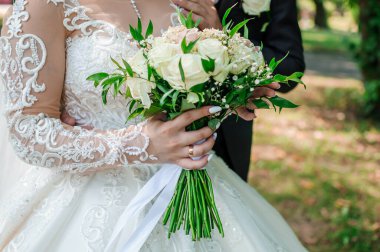 Zarif bir gelin elinde beyaz güller ve bebek nefesi ile kısmen görünür bir damat, açık hava bahçesinde romantik bir düğün sahnesi sergiliyor..