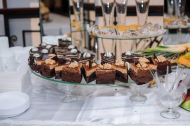 Bir düğün resepsiyonunda ziyafete katılan müsrif bir tatlı çeşitli çikolatalı browniler, meyve düzenlemeleri ve şampanya bardakları, neşeli bir atmosfer yaratıyor..