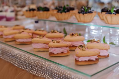 Zarif pembe kremalı kurabiyeler pırıl pırıl gümüş bir tepside lüks bir tatlı masasında düzenlenir. Zarif hamur işleri ve müsrif bir kutlama sergilenir..