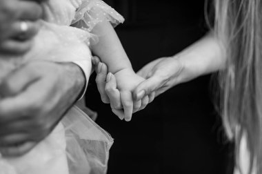 Dokunaklı siyah beyaz bir fotoğraf, genç bir çocuğun bir yetişkinle el ele tutuşmasını, sevgiyi, güveni ve bağlantıyı simgeleyen bir anı yakalar.