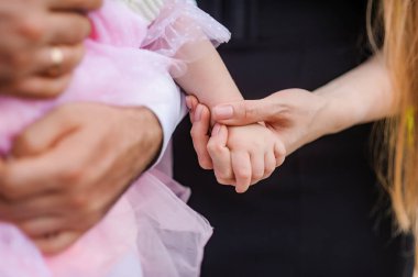 Koyu tenli bir adam ve açık tenli bir kadın olarak, narin pembe elbiseli genç bir kızın küçük ellerini nazikçe tutarak, aşkı ve bağlantıyı ifade eden samimi bir an..