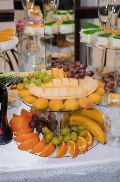 Karpuz, üzüm, portakal, muz ve hamur işleri gibi taze meyvelerin sergilendiği zarif bir düğün tatlı masası, beyaz çarşaflarda sergileniyor..