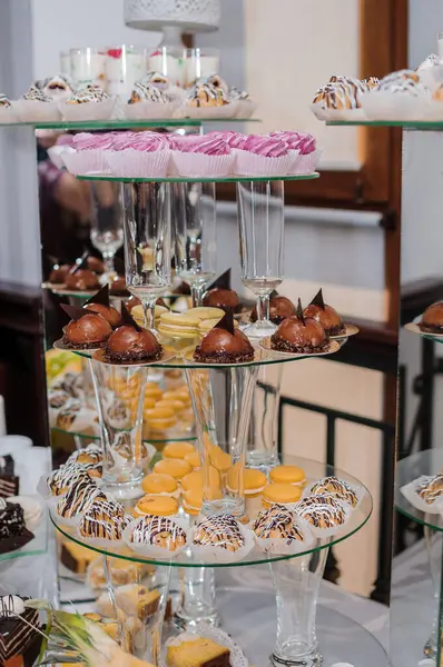 Bir etkinlikte renkli kekler, çikolatalı şekerler, badem kurabiyeleri ve şampanya kadehleriyle dolu gösterişli bir tatlı sergisi..