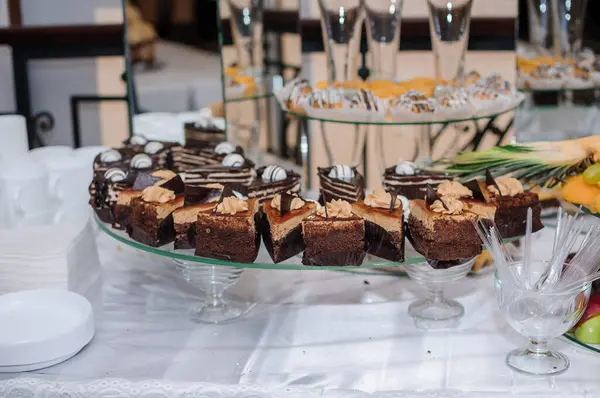 Bir düğün resepsiyonunda ziyafete katılan müsrif bir tatlı çeşitli çikolatalı browniler, meyve düzenlemeleri ve şampanya bardakları, neşeli bir atmosfer yaratıyor..