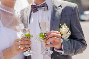 Gelin ve damadın düğün kutlamaları sırasında şampanya kadehleri tutarken, mutluluğu, aşkı ve bağlılığı gösteren yakın çekim görüntüsü.