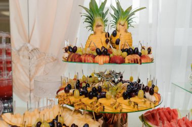 İki katlı güzel bir meyve tabağı renkli bir ananas, üzüm, böğürtlen, şeftali ve dilimlenmiş meyve karışımını sunar.