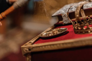 Zengin bir tören sahnesinde tütsü tütsülenirken mücevherli bir taç ve kırmızı kadife üzerine kurulmuş kutsal bir kadeh maneviyat ve dini gelenek tasvir edilir.