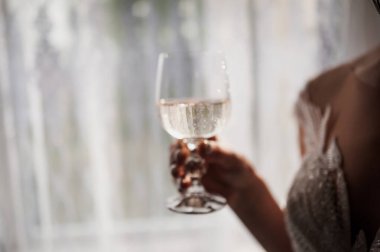 Bulanık, yakın plan bir görüntü elinde şampanya kadehiyle ışıltılı bir elbise içinde bir düğün ya da lüks bir kutlama olduğunu ima eden bir kadın yakalıyor.