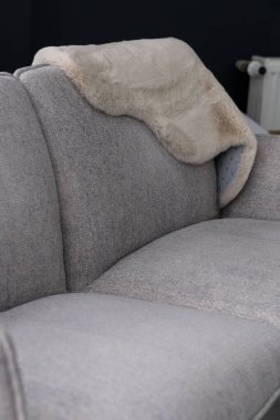 Sırtüstü örtülmüş yumuşak, sahte kürklü gri kumaştan bir kanepe. İç tasarım kavramları için rahat bir oturma odası sahnesi.