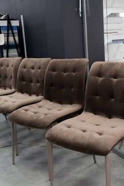 Metal bacaklı ve klasik düğmeli altı sıra rahat kadife yemek koltuğu minimalist bir iç sergi salonunda sergileniyor.