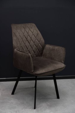 Elmas desenli yorgan ve parlak siyah metal bacaklı rahat bir gri kadife koltuk yemek odaları veya yaşam alanları için çağdaş bir oturma yeri sunar.