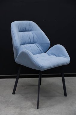 Bu resim, parlak mavi döşemeli, parlak siyah metal bacaklı, nötr gri zeminli, çağdaş mobilyaları ve minimalist ev dekorunu gösteren bir aksanlı sandalyeyi gösteriyor.