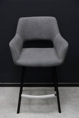 Rahat gri döşemeli, arkası açık ve parlak siyah metal bacaklı bir yemek sandalyesi, mutfak adaları, modern restoranlar veya ev barları için minimalist koltuklar sağlar.