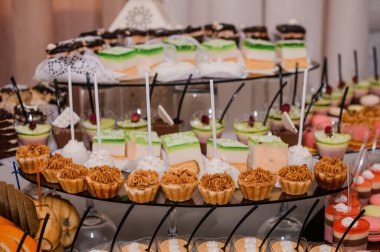 Müsrif bir tatlı masası renkli kekler, küçük pastalar, canlı meyveler ve cazip şekerlemeler ile dolup taşıyor. Kutlama etkinlikleri ve düğünler için cazip bir ziyafet sunuyorlar.