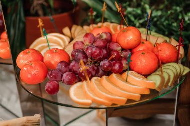 Portakallar, kırmızı üzümler ve ananas dilimlerinden oluşan renkli bir meyve tabağı dekoratif kürdanlarla güzel bir şekilde düzenlenmiştir.
