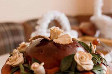 Zarif krema gülleri ve parlak çikolata jöleleriyle süslenmiş güzel dekore edilmiş bir çikolatalı pasta, bir düğün tatlı masasında dinleniyor, kırsal bir zarafet sergiliyor.