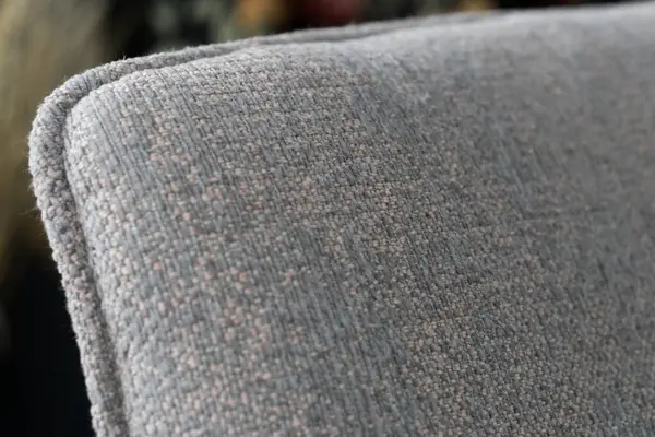 Koltuğun yakın plan görüntüsü, ince pembe benekli, dokulu gri döşeme kumaşı, rahatlığı ve modern iç tasarım tarzlarını gözler önüne seriyor.