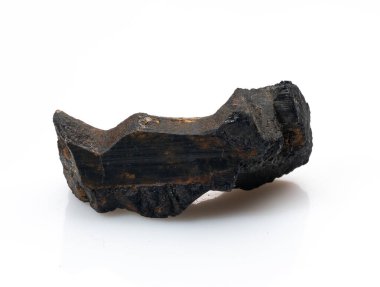 Kaba, işlenmemiş siyah bir turmalin kristal parçası belirgin bir şekilde beyaz bir arkaplan karşısında duruyor, doğal, çizgili dokusu ve derin, gölgeli rengi sergiliyor.