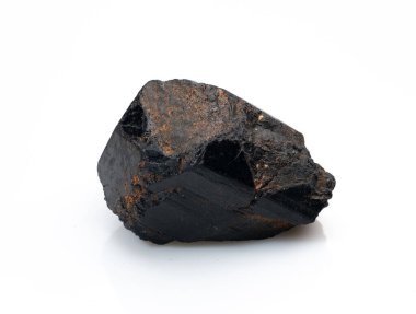 Kabaca kesilmiş siyah bir turmalin kristalini metalik beneklerle yakından çekerek, temiz beyaz bir arkaplana karşı doğal formunu sergiliyor.