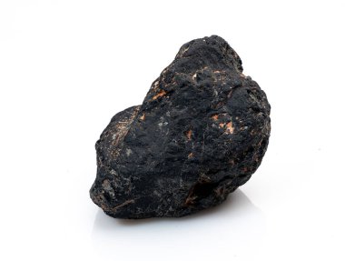 Çarpıcı, cilalanmamış bir siyah turmalin kristali el değmemiş beyaz bir zemin üzerinde duruyor. Eşsiz, koyu dokusunu ve büyüleyici turuncu beneklerini sergiliyor.