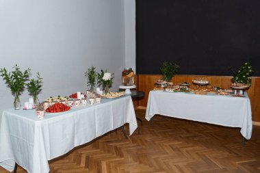 Çilekler, pastalar, katlı stantlar ve çiçeklerin yer aldığı güzel bir tatlı büfesi. Düğünler, partiler ya da beyaz çarşaflarla süslenmiş kutlama etkinlikleri için mükemmel.