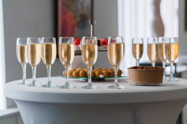 Güzel bir set masasında, bir kase taze çileğin yanında altın köpüklü sıvıyla dolu sıra sıra şampanya bardakları ve lüks bir parti ortamı oluşturur.