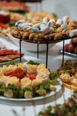 Müsrif bir açık büfe, kruvasan, minyatür sosis, sanatsal olarak düzenlenmiş peynir gülleri ve renkli pastalar gibi lezzetli ziyafetlerle dolu kademeli tabaklar sunar. Düğünler için mükemmeldir.