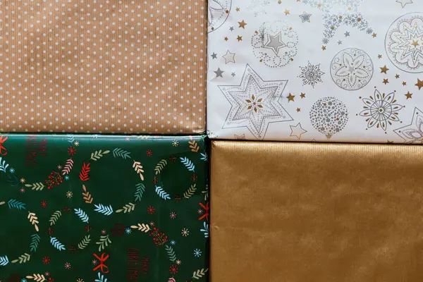 Yıldızlar, benekler ve dallar gibi çeşitli Noel ambalaj kağıtları hediye verme ve tatil sezonu pazarlaması için ideal koyu bir yüzeyde sergileniyor.