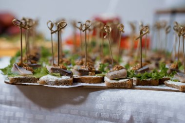 Yakın plan çekimde beyaz keten masa örtüsüne yerleştirilmiş, üzerinde mantarlı crostini ve kremalı sosla servis için mükemmel bir sofra örtüsü var.