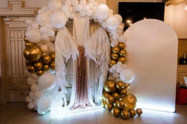 Tüylü melek kanatlarına sahip zarif bir altın ve beyaz balon kemeri partiler, düğünler ya da lüks bir iç mekan içindeki kutlamalar için çarpıcı bir zemin oluşturur.