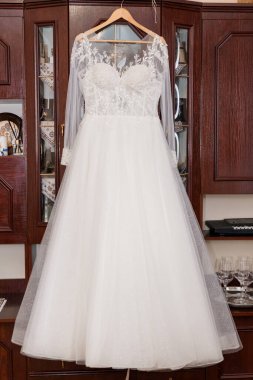 Uzun kollu, güzel beyaz dantelli bir gelinlik, bir askıya asılı, camlarla dolu bir kiraz ağacının önünde, romantik bir düğün havasını çağrıştırıyor.