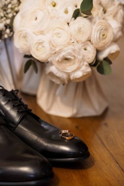 Damadın özel aksesuarlarının, bağcıklarda dinlenen siyah ayakkabıları ve yemyeşil beyaz Ranunculus buketi, aşkı ve bağlılığı simgeliyor.