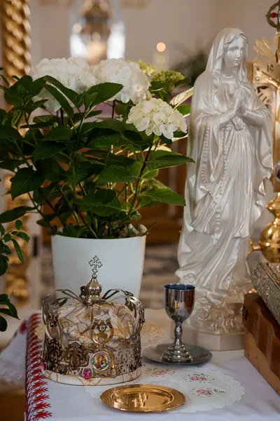 Meryem Ana 'nın ortancalarla süslenmiş beyaz bir heykeli, kilisenin sunağında altın bir taç ve kadeh, inancı ve maneviyatı simgeliyor.