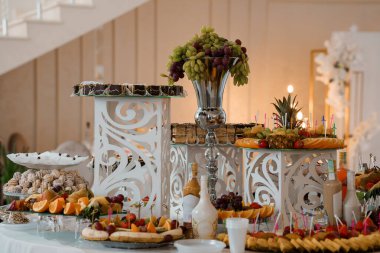 Müsrif düğün tatlıları taze üzümler, ananaslar, pastalar ve renkli şekerlerle dolu katmanlı vitrinler, etkinlik planlama ve kutlama görselleri için ideal.