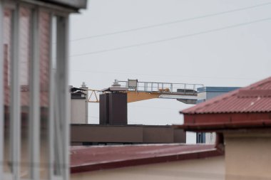 Bir inşaat vinci donuk gri bir gökyüzünün altında, inşaat ve şehir gelişimine odaklı kentsel bir inşaat sahası gösteriyor.