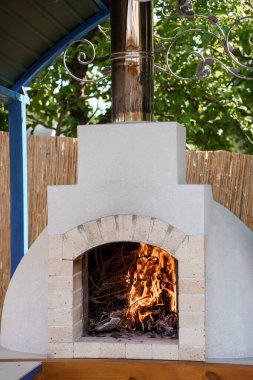 Sıcak, tuğladan yapılmış bir pizza fırını, bilfiil kemerli bir muhafaza içinde ahşap yakıyor. Gurme yemekleri, arka bahçe eğlencesi ve kırsal bahçe estetiği için ideal.