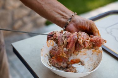 Yakın plan bir vitrin, beyaz bir kasede çiğ kuzu etini baharat ve karıştırma, ızgara için şiş hazırlama, yemek hazırlama veya Akdeniz mutfağını temsil eden eller.