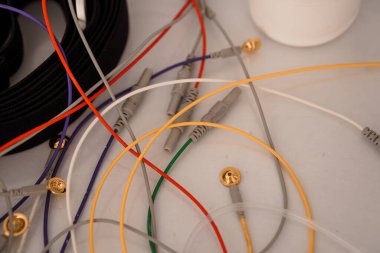 Bir polisomnografi sisteminin karmaşık kabloları çeşitli renkli elektrot bağlantıları ve beyaz plastik tabanı da dahil olmak üzere tanısal süreçleri gösteren sergilenmektedir.