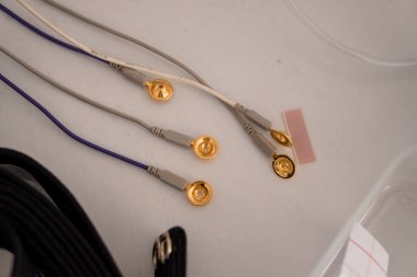 Bir polisomnografi uyku çalışması sırasında beyaz bir hasta yüzeyine bağlı mavi kablolar ile EEG elektrot bağlantılarının detaylı yakın çekim görüntüsü, teşhis testlerini vurguluyor