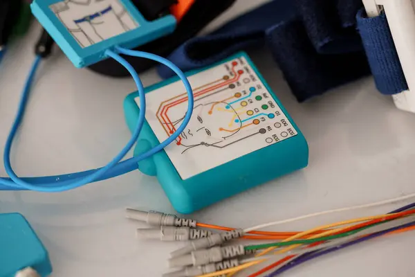 Bir polisomnografi makinesinin yakın çekim görüntüsü çeşitli renkli kablolarla bağlanmış, bu da tıbbi teşhislerde ve hasta gözetiminde kullanılan bir uyku çalışma düzenini gösteriyor