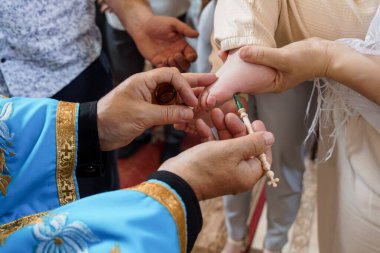 Dini ayinlerin samimi anlarında, bir Doğu Ortodoks rahibi vaftiz töreni sırasında kutsal yağ ile bebek ayağı yağını kutsuyor ve inanca odaklanıyor.
